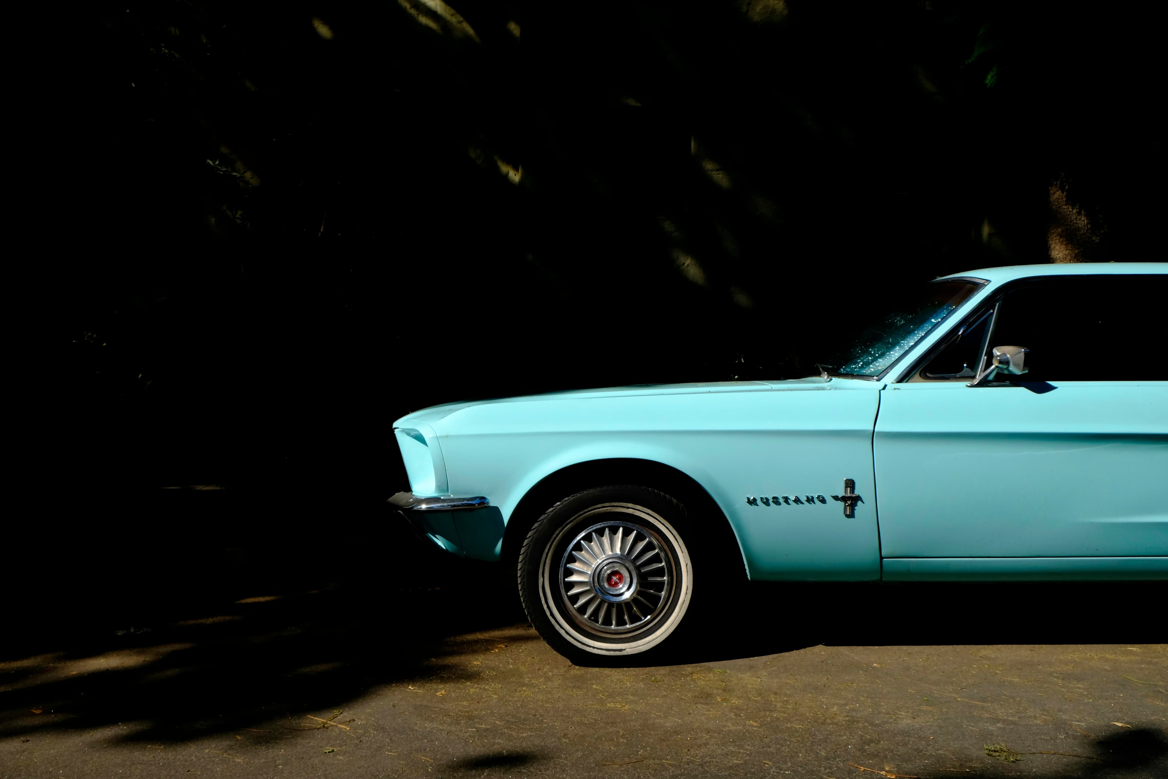 Teal 1960s Ford Mustang parked at the curb in warm afternoon light