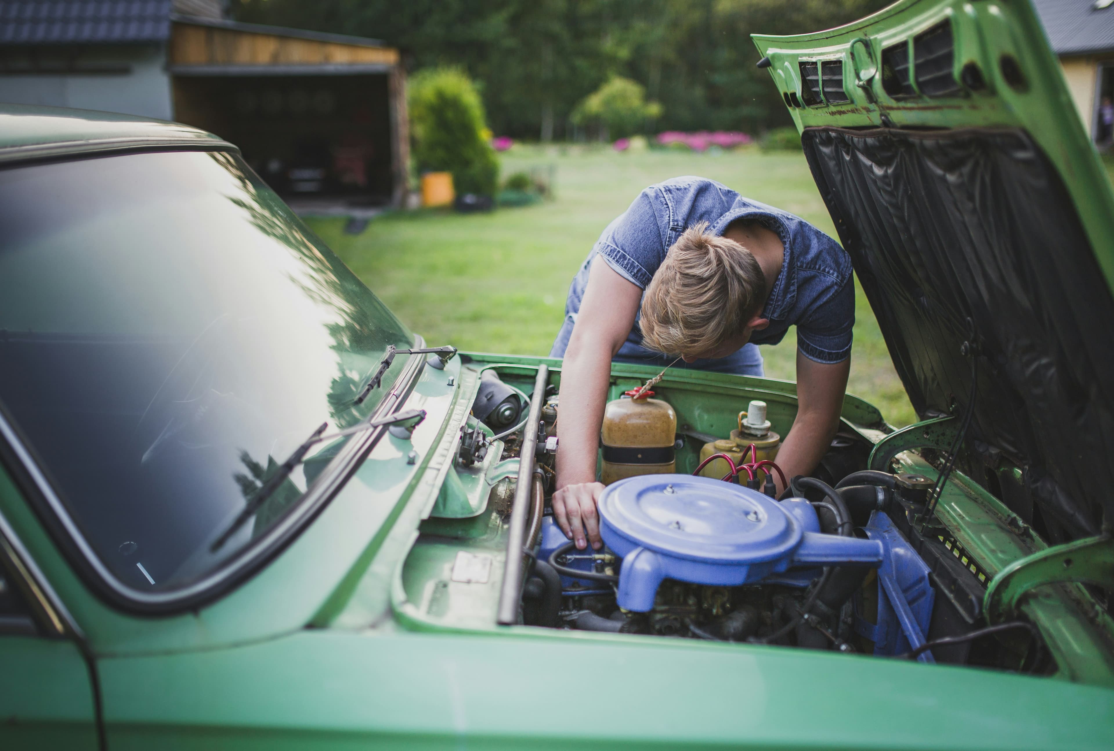 Mechanic checking a car engine with the hood open at the roadside